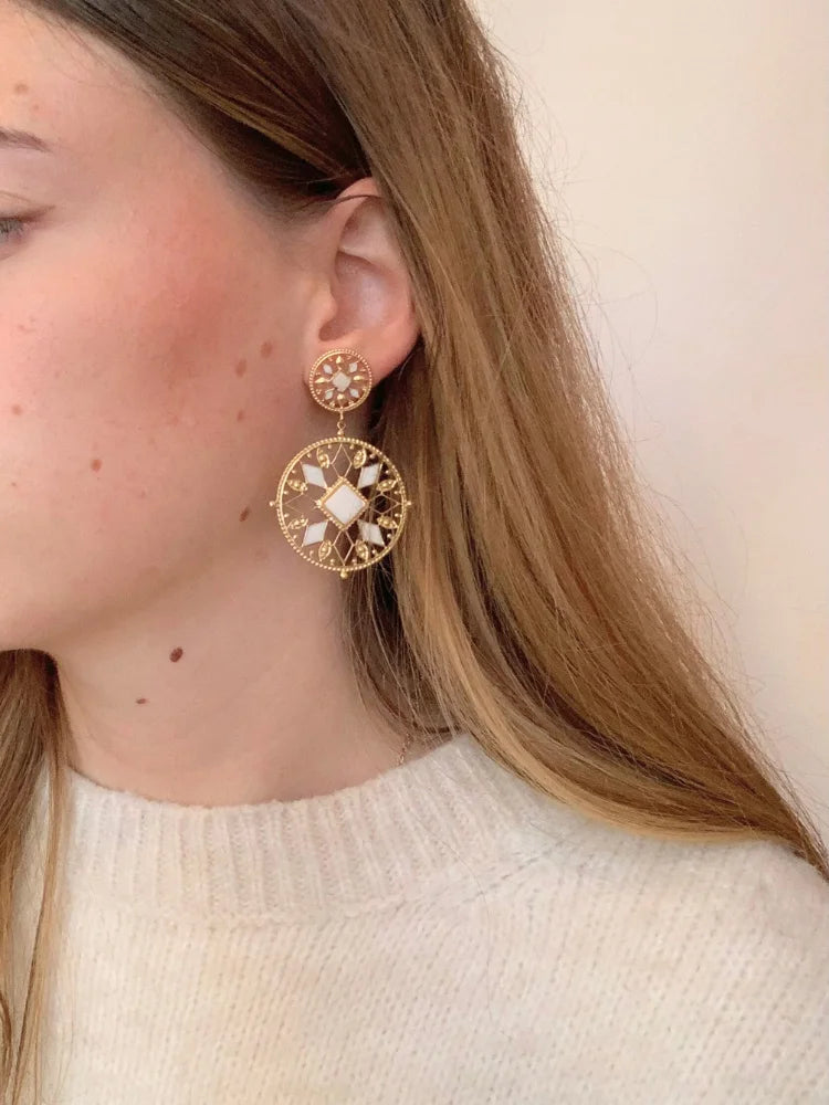 La femme porte les boucles d'oreilles Alya dorées en acier inoxydable de chez Au Bonheur de Sophie