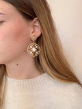 La femme porte les boucles d'oreilles Alya dorées en acier inoxydable de chez Au Bonheur de Sophie